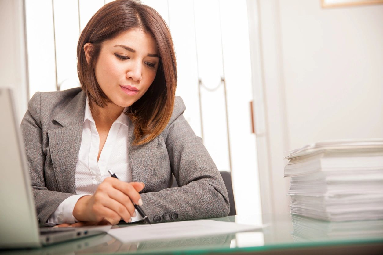 Woman working at a desk with documents.