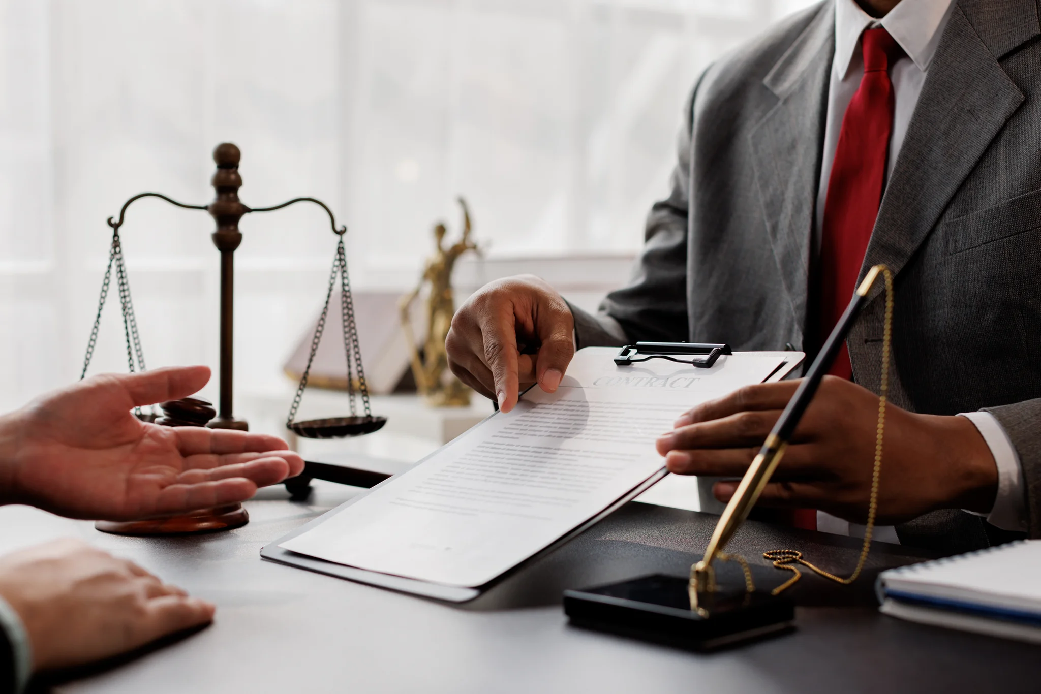 Lawyer discussing contract with client, scales visible.