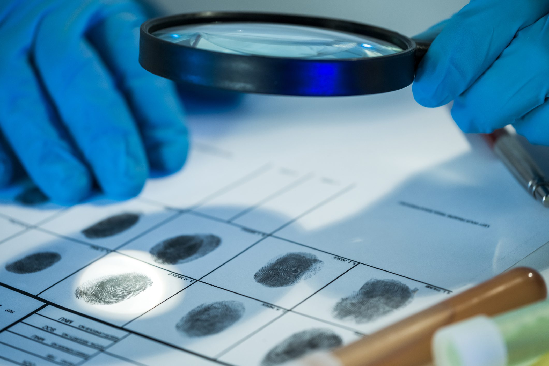 Magnifying glass examining fingerprints on paper.