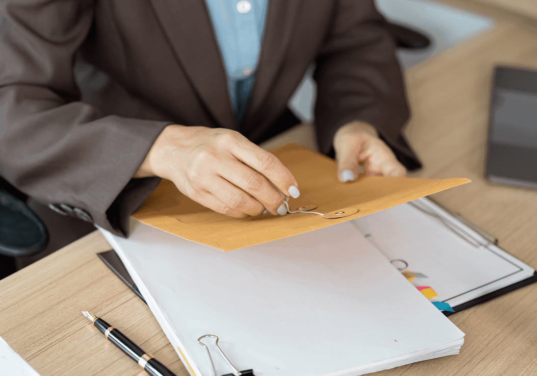 Person opening a brown envelope at desk.