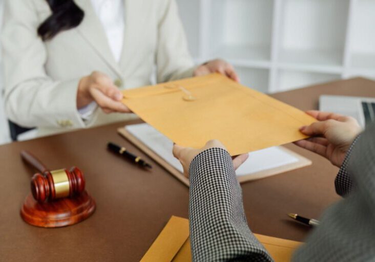 Hands exchanging envelope at office desk.